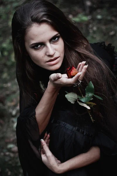 Strega di Halloween in una foresta buia. Bella giovane donna in costume da strega. Sfondo di orrore per il concetto di Halloween — Foto Stock