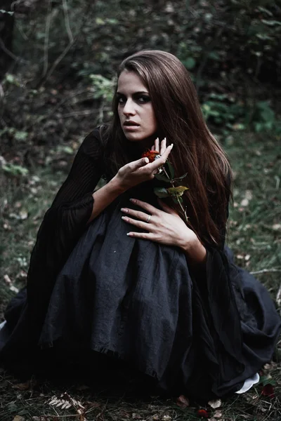 Halloween häxa i en mörk skog. Vacker ung kvinna i häxor kostym. Horror bakgrund för Halloween koncept — Stockfoto