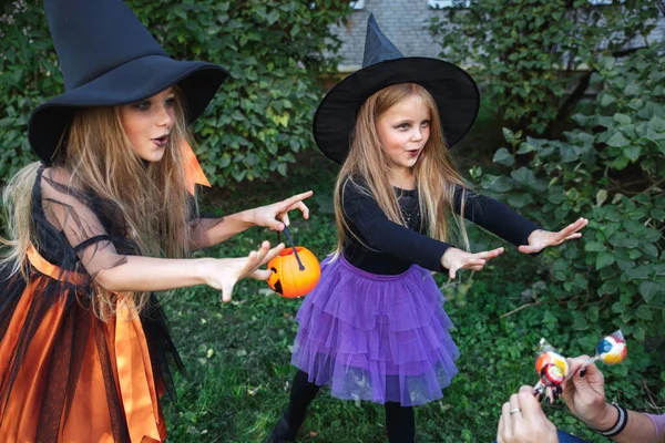 Pequenas crianças enganam ou tratam. Duas pequenas bruxas assustam o vizinho no Halloween — Fotografia de Stock