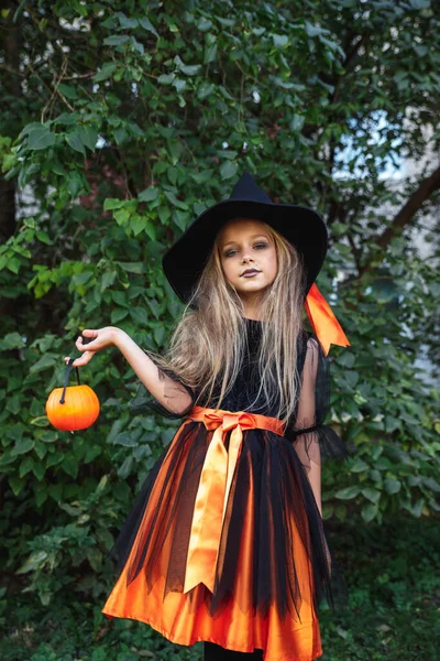 Menina engraçada em traje de bruxa para o Halloween com abóbora Jack ao ar livre — Fotografia de Stock