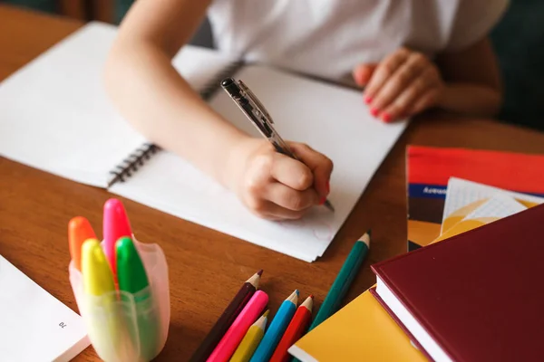Holčička dělá domácí úkoly a čte si doma. Selektivní měkké zaměření na ruce — Stock fotografie