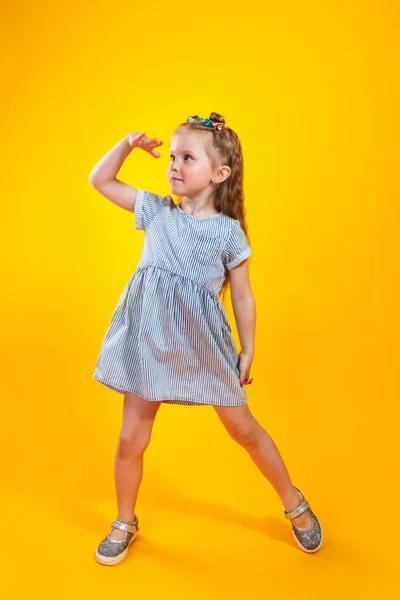 Linda niña mirando lejos con la mano sobre la cabeza sobre fondo amarillo — Foto de Stock