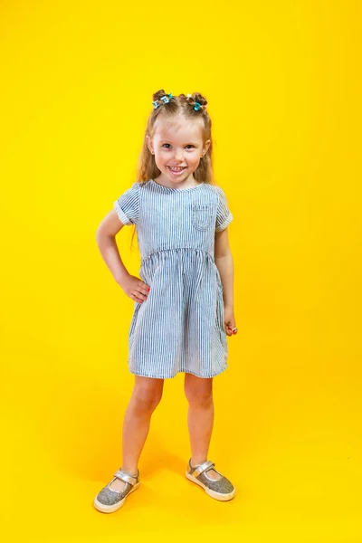 Αξιολάτρευτο κοριτσάκι με μοντέρνο φόρεμα που ποζάρει σε κίτρινο φόντο — Φωτογραφία Αρχείου