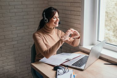 Genç kız öğrenci kulaklık takıyor. Webinar izliyor. İnternetten ders dinliyor ve dil öğreniyor.