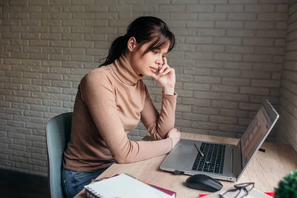 Mujer pensativa sentada en la mesa de trabajo en el portátil pensando en la solución de problemas de negocios — Foto de Stock