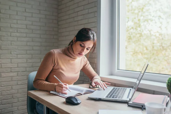 Šťastná hispánská mladá žena nosí brýle pomocí notebooku pracuje na domácí kanceláři — Stock fotografie