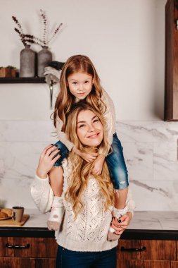 Gülümseyen anne evdeki mutfakta çocukla oynuyor.