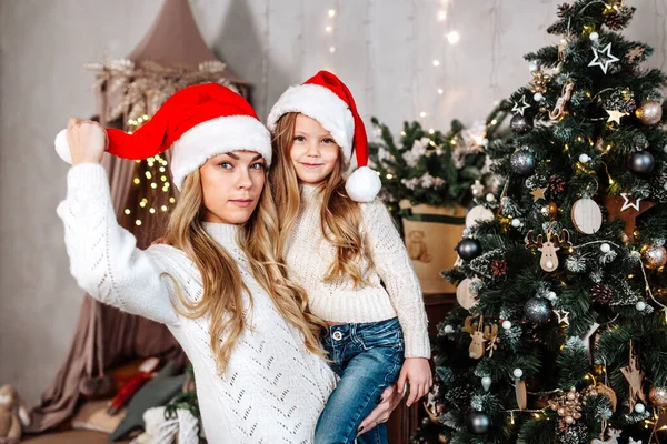 Matka i córka w kapeluszach Świętego Mikołaja bawią się w czasie świąt Bożego Narodzenia — Zdjęcie stockowe