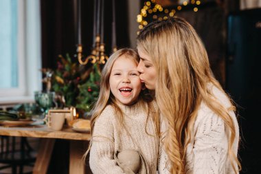 Mother kissing little daughter at christmas time