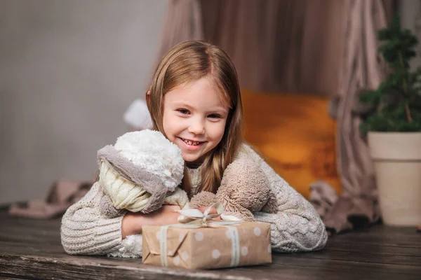 Cutre little girl lying among Christmas gifts at home .