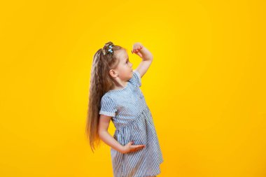 Funny little girl looking ahead on yellow background