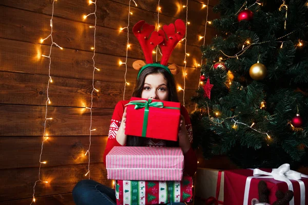 Feliz joven en caja de regalo de apertura de sombrero de santa en el hermoso árbol de Navidad de oro con luces en casa — Foto de Stock