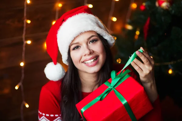 Mujer joven sonriente sosteniendo regalo de Navidad en casa — Foto de Stock