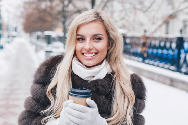 Mujer joven bebiendo café caliente y caminando en la fría ciudad de invierno —  Fotos de Stock