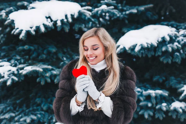 Dia dos Namorados. Mulher sorridente bonita segurando coração vermelho nas mãos na floresta . — Fotografia de Stock