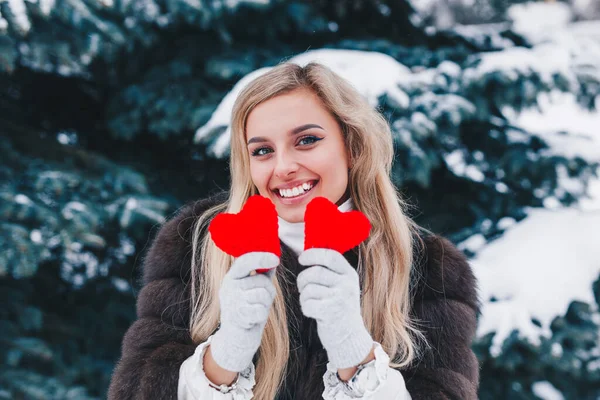 Día de San Valentín. Bella mujer sonriente sosteniendo corazones rojos en las manos en el bosque . —  Fotos de Stock
