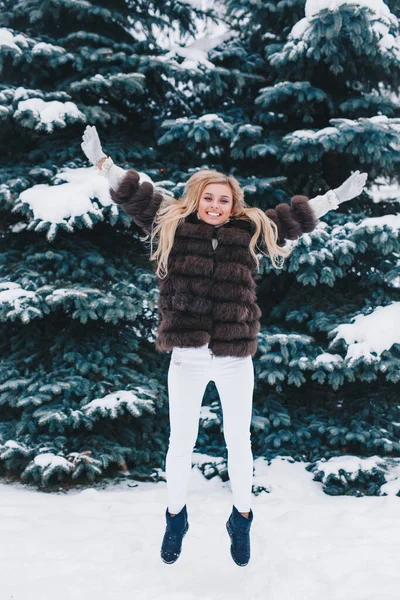 아름다운 아가씨가 겨울 눈덮인 숲에서 뛰고 있습니다 — 스톡 사진