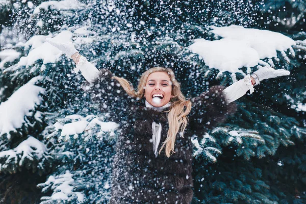 Menina feliz em roupas quentes brincando com neve ao ar livre na floresta de inverno — Fotografia de Stock