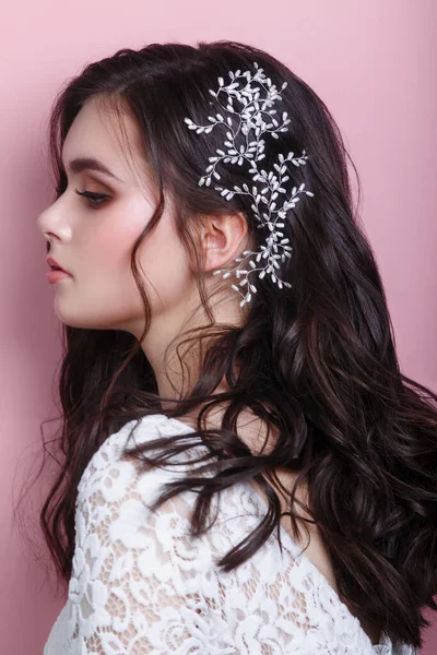 Retrato de hermosa mujer modelo de boda con joyas en el cabello mirando hacia otro lado sobre fondo rosa —  Fotos de Stock