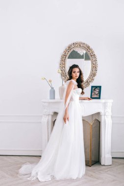 Gelinlikli göz kamaştırıcı gelin stüdyoda duruyor.