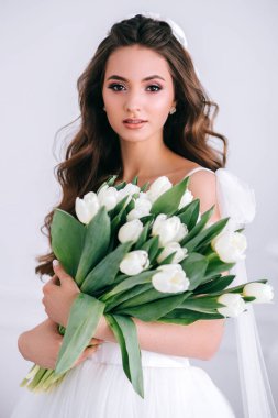 Stüdyoda elinde bir buket beyaz lale tutan güzel gelin. Üreme Günü