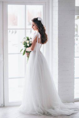 Gelin olarak güzel esmer kadın stüdyoda düğün buketi ile