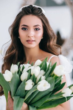 Stüdyoda elinde bir buket beyaz lale tutan güzel gelin. Üreme Günü