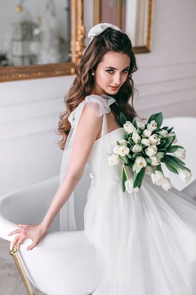 Young bride in wedding dress holding bouquet of white tulips in studio — Stock Photo, Image