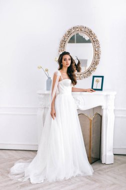 Gelinlikli göz kamaştırıcı gelin stüdyoda duruyor.