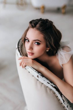 Gelinlikli güzel romantik gelin stüdyoda oturuyor.