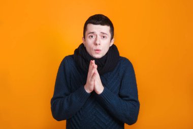 Kalın elbiseli bir adam sarı arka planda çok soğuk hissediyor.