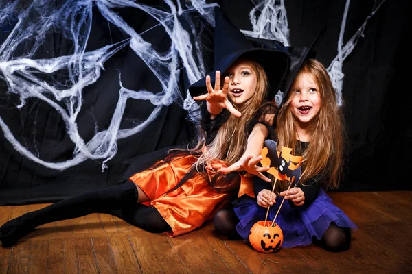 Twee kleine meisjes in heksenkostuums die plezier hebben met Halloween. Snoep of je leven — Stockfoto