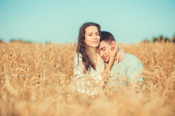 Jeune couple amoureux en plein air.en été dans le champ.Couple câlins. Jeune beau couple amoureux rester et embrasser sur le terrain au coucher du soleil. Couleurs douces et ensoleillées. Beau couple couché sur le verre — Photo