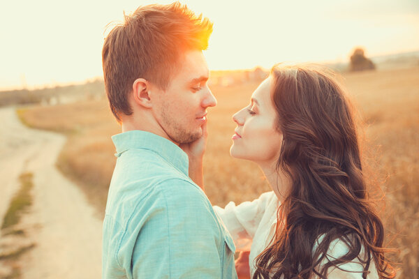 Молодая пара влюблена на открытом воздухе. Потрясающий чувственный открытый портрет молодой стильной моды пара позирует летом в поле
