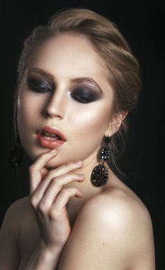 Beauty Woman with Perfect Makeup. Beautiful Professional Holiday Make-up. Glamorous Woman. Fashion model with jewelry, modern natural make up. Black background.
