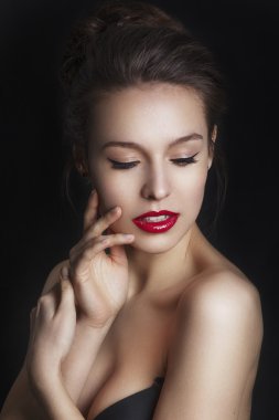 Beautiful smiling young model with red lips and red manicure on black background. Happy model girl
