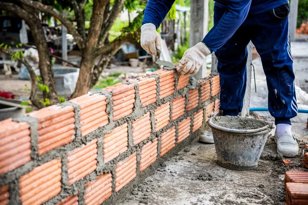 Bauarbeiter verlegt Ziegel auf Baustelle. lizenzfreie Stockfotos