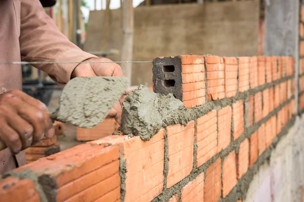 Bauarbeiter verlegt Ziegel auf Baustelle. Stockbild