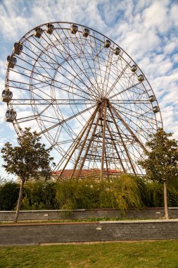 Güneşli bir günde Sochi Parkı 'nda beyaz bulutlu mavi gökyüzüne karşı dönme dolap. 