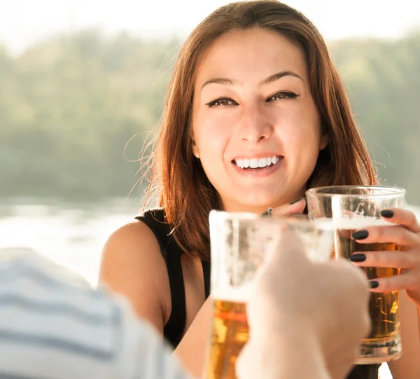 En ung, smilende kvinne som drikker et glass verneøl – stockfoto