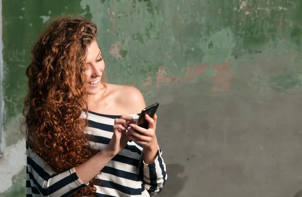 Akıllı telefon kullanan genç gülümseyen kadın