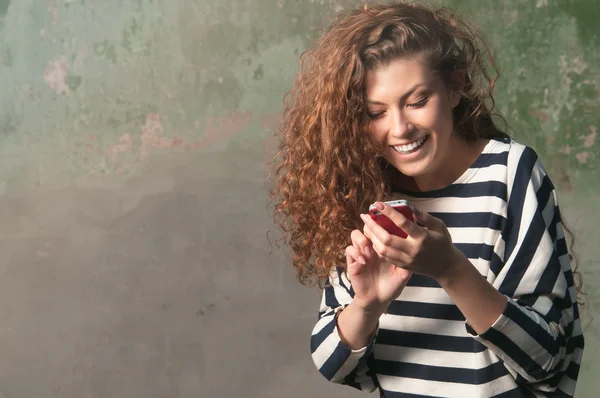 Jonge lachende vrouw met behulp van smartphone Rechtenvrije Stockafbeeldingen