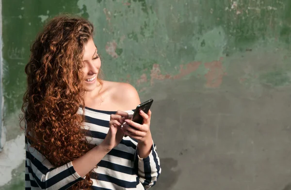Молодая улыбающаяся женщина с помощью смартфона Стоковое Фото