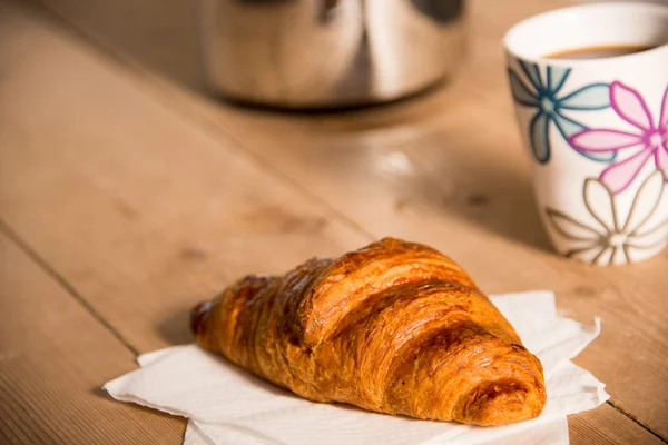 Croissant och mugg kaffe på bordet Stockbild