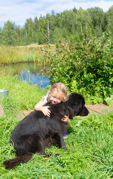 Uma Menina Abraça Grande Cão Preto — Fotografia de Stock