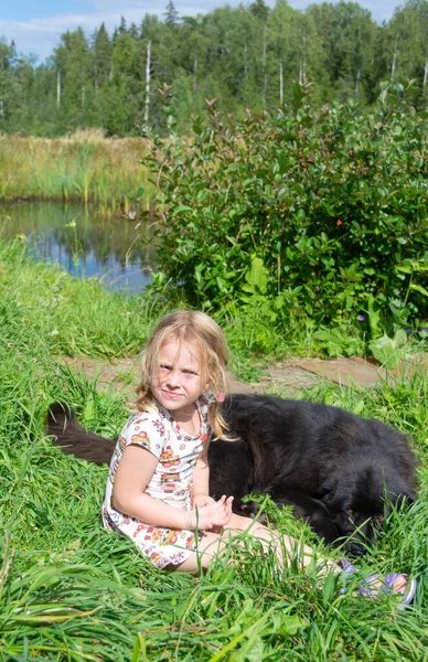 Uma Menina Abraça Grande Cão Preto — Fotografia de Stock