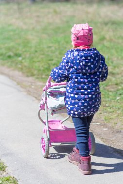 Bir kız bebek arabasıyla sokakta yürüyor ve güzel havanın tadını çıkarıyor.. 