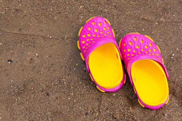 Çocukların pembe takunyaları sahile yakın bir kumsalda duruyor..