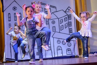 Çocuklar sahnede güzel parlak kostümlerle dans ediyorlar. İlginç bir dans..