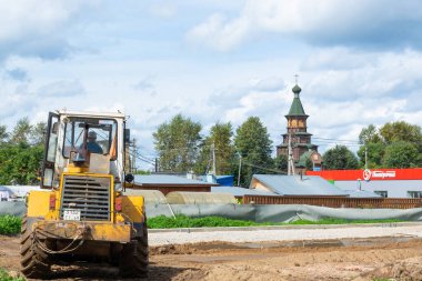 Sarı tekerlekli bir traktör buldozer tamir çalışmalarının yapıldığı yerde caddede duruyor.. 